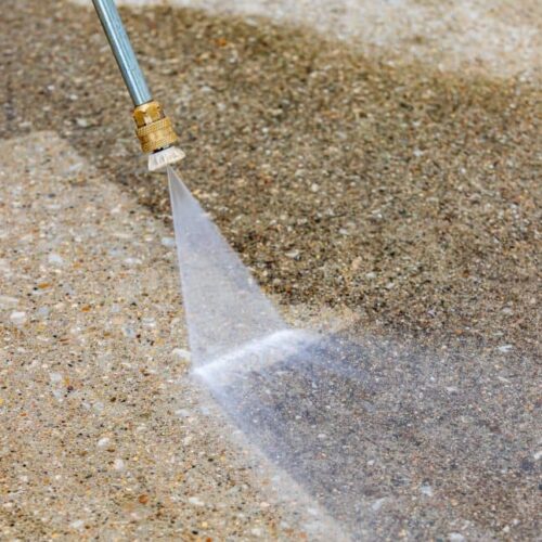 Cleaning driveway using power washer.